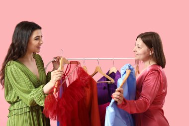 Young women choosing prom dresses on pink background clipart
