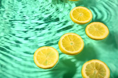 Turkuaz arka planda suda taze limon dilimleri