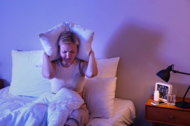 Yastıklı genç bir kadın geceleri yatakta uyuyamaz.