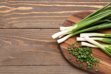 Ahşap zemin üzerinde taze taze soğan dilimleri olan tahta.