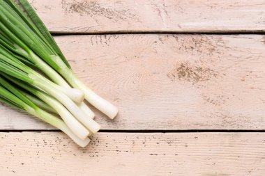 Beyaz ahşap zemin üzerinde taze yeşil soğan
