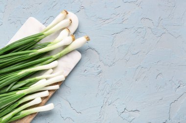 Mavi zemin üzerinde taze yeşil soğan olan tahta