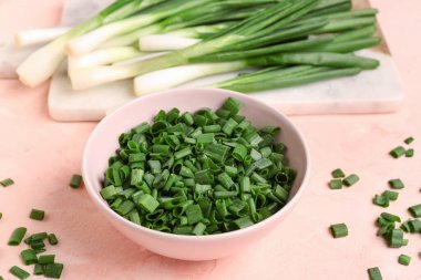 Pembe arka planda taze yeşil soğanlı bir kase dilimler ve yiyecek.