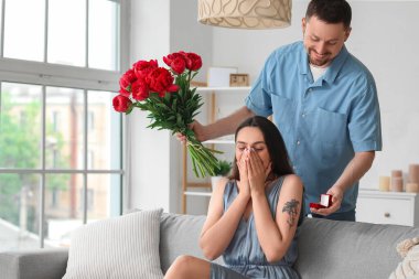 Çiçekli genç adam kız arkadaşına evlenme teklif ediyor.