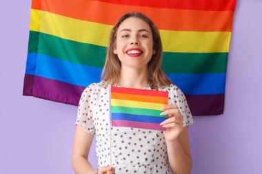 Leylak arka planında LGBT bayrakları olan genç bir kadın.