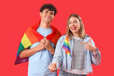 Kırmızı arka planda LGBT bayrakları olan genç bir çift