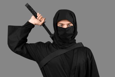 Gri arkaplanda katana olan erkek ninja.