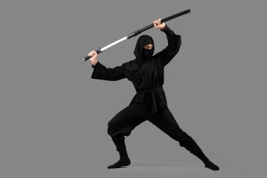 Male ninja with sword on grey background clipart