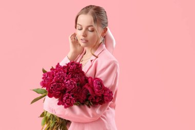 Pembe arka planda şakayık çiçekleri olan güzel bir kadın.