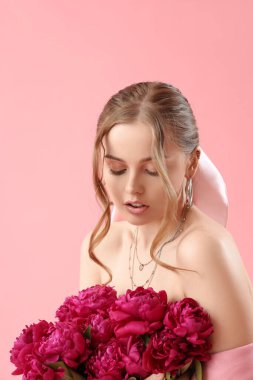 Pembe arka planda şakayık çiçekleri olan güzel bir kadın.