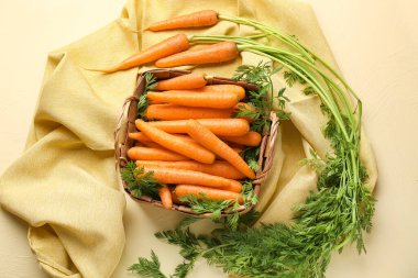 Bej arka planda taze havuç dolu hasır sepet.