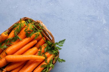 Mavi arka planda taze havuç dolu sepet.