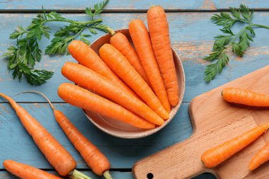 Mavi ahşap arka planda taze havuç ve kâse.