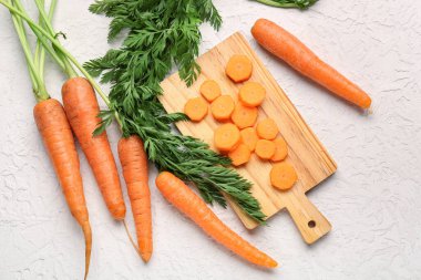Beyaz arka planda taze havuç dilimleri olan tahta.