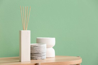 Renkli duvarın yanındaki masada bir şişe sazlık ve dekor var.