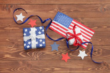 ABD bayrağı ve kahverengi ahşap arka planda kurdele bulunan hediye kutuları. Amerikan Bağımsızlık Günü