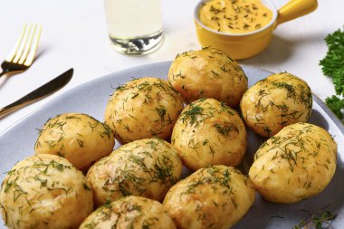 Beyaz arka planda dereotlu ve soslu haşlanmış bebek patatesleri.