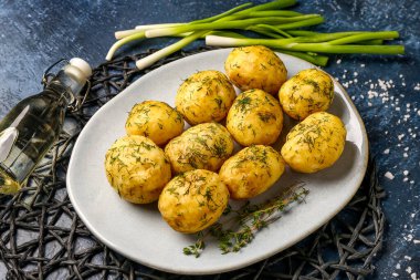 Mavi zemin üzerinde dereotu ve yeşil soğanlı haşlanmış bebek patatesler.