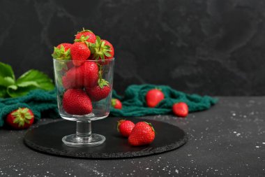 Siyah arka planda taze çilek dolu bir tahta.