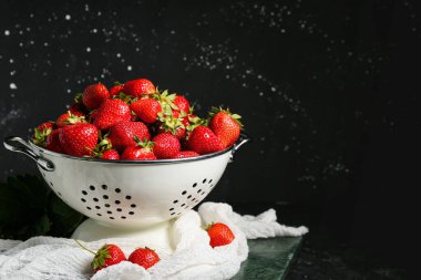 Siyah arka planda taze çilekli Colander.