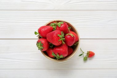 Beyaz ahşap arka planda taze çilek kasesi.