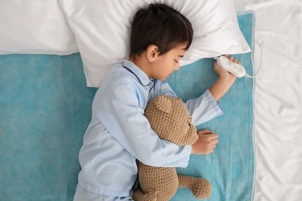 stock image Little boy with toy sleeping on electric heating pad in bedroom