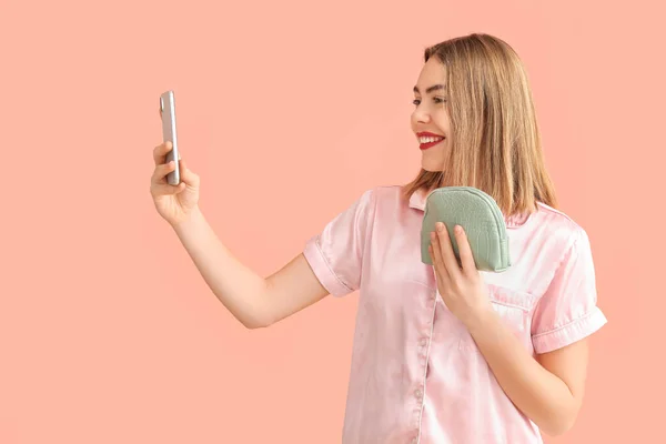 Молодая Женщина Косметической Сумкой Мобильным Телефоном Делает Селфи Розовом Фоне — стоковое фото