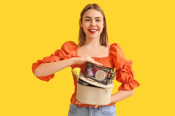 Junge Frau Mit Kosmetiktaschen Auf Gelbem Hintergrund — Stockfoto