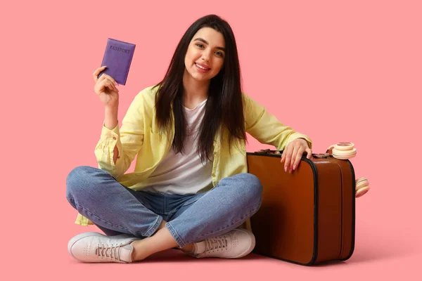Молода Жінка Паспортом Валізою Сидить Рожевому Фоні — стокове фото