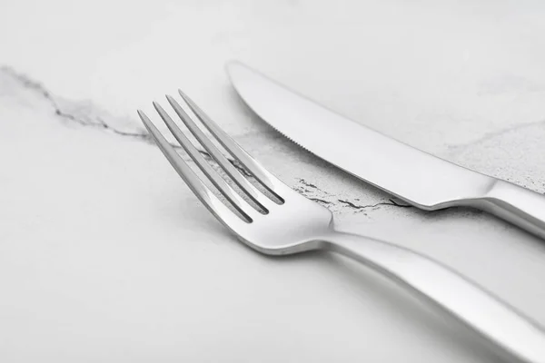 白い大理石のテーブルの上のフォークとナイフ クローズアップ — ストック写真