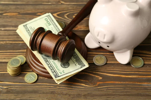 茶色の木製の背景に裁判官のギャベルとお金を持つ貯金箱 破産の概念 — ストック写真