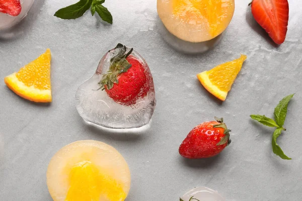 Frische Erdbeeren Und Orangenstücke Eingefroren Eis Auf Grauem Hintergrund — Stockfoto