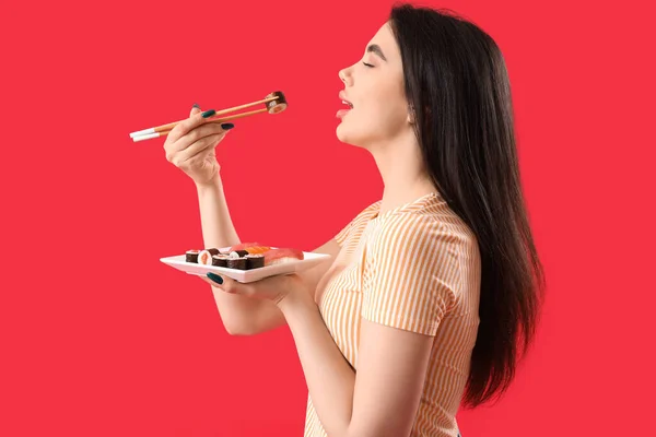 Νεαρή Γυναίκα Τρώει Σούσι Ρολά Κόκκινο Φόντο — Φωτογραφία Αρχείου