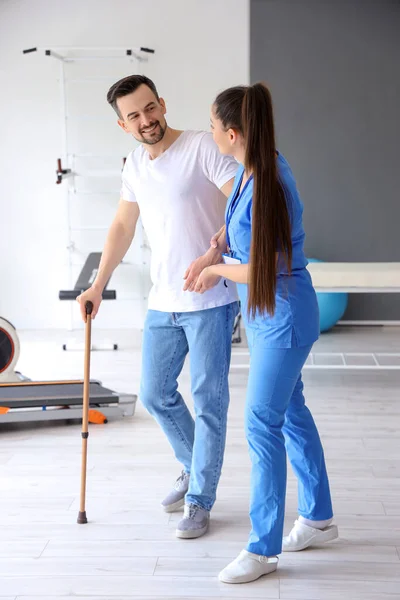 Female Physiotherapist Helping Young Man Walking Stick Rehabilitation Center — Stock Photo, Image