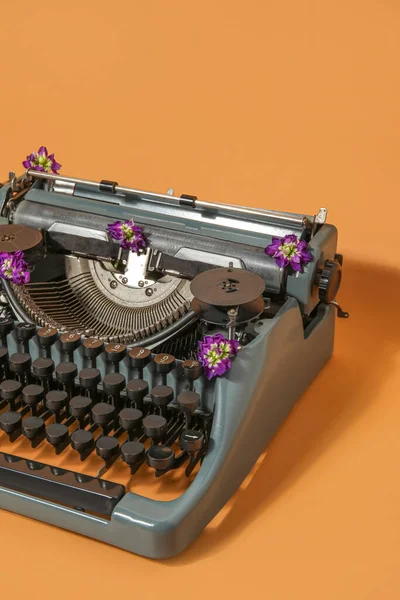 Mesin Ketik Vintage Dengan Bunga Ungu Pada Latar Belakang Oranye — Stok Foto