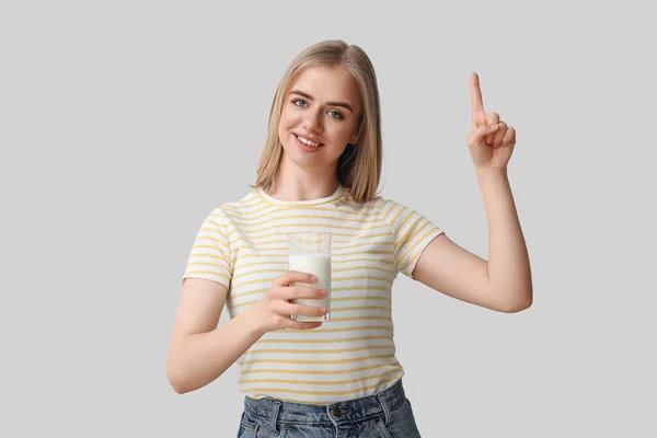 Όμορφη Νεαρή Γυναίκα Ένα Ποτήρι Γάλα Που Δείχνει Κάτι Γκρι — Φωτογραφία Αρχείου