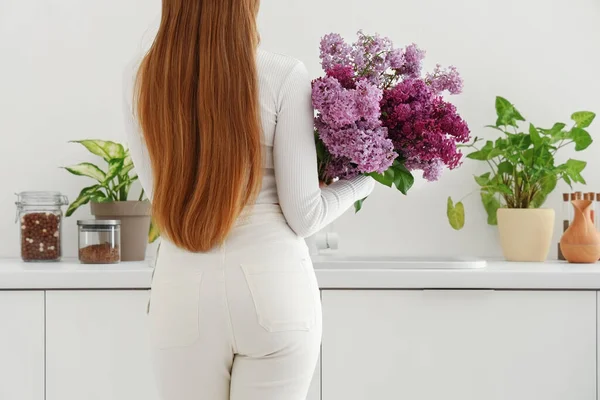 Young Woman Lilac Flowers Kitchen Back View — Stock Photo, Image