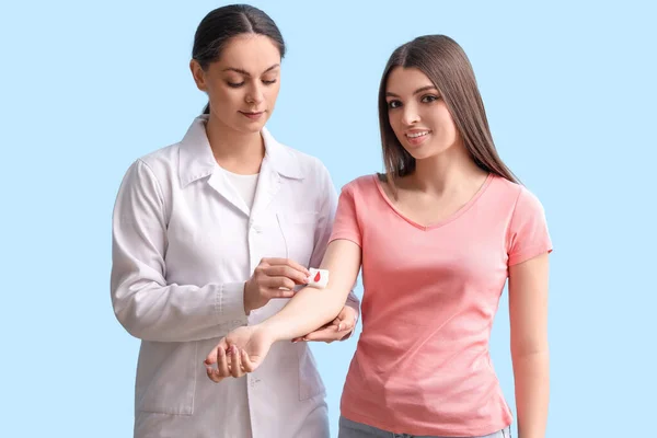 Kvinna Läkare Tillämpa Gasbinda Blodgivarens Arm Mot Blå Bakgrund — Stockfoto