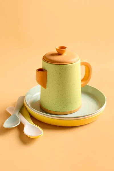 Teapot Plates Spoons Baby Pale Orange Background — Stock Photo, Image