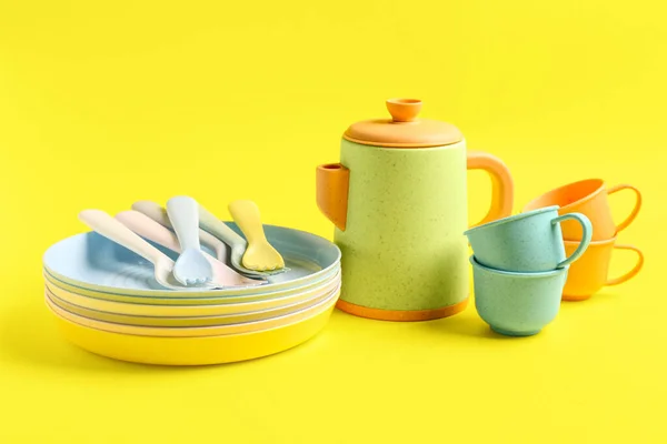 Different eating utensils for baby on yellow background