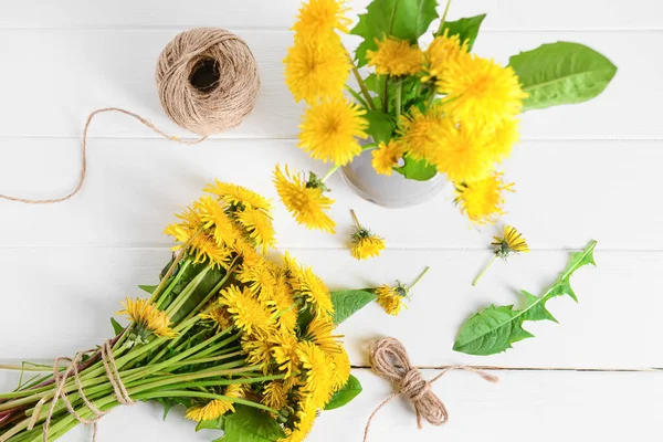 Yellow dandelion flowers and rope on light wooden background