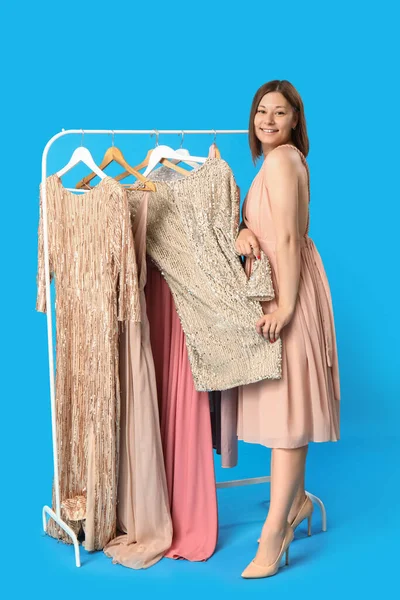 Stock image Young woman choosing prom dress on blue background