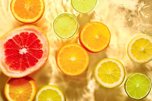 Diferentes Fatias Frutas Cítricas Água Fundo Amarelo — Fotografia de Stock