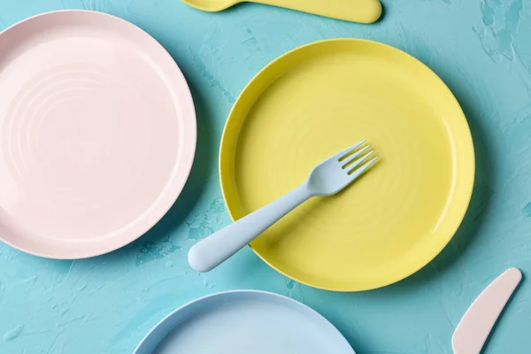 Colorful plates with eating utensils for baby on grunge blue background