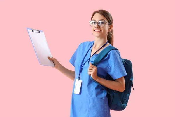 女性医療インターンとともにクリップボードとバックパック上のピンクの背景 — ストック写真