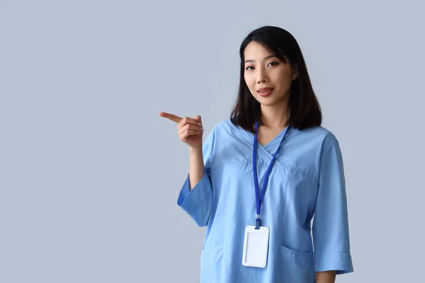 Kvinnelig Asiatisk Praktikant Som Peker Noe Grå Bakgrunn – stockfoto
