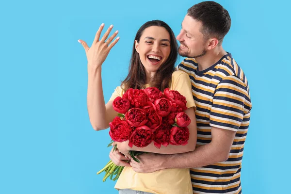 Šťastný Zasnoubený Pár Květinami Modrém Pozadí — Stock fotografie