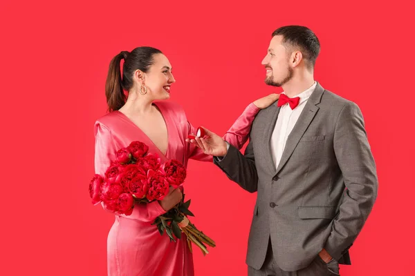 Fiatal Férfi Megkéri Barátnője Virágok Piros Háttér — Stock Fotó