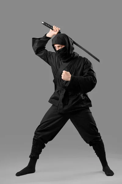 stock image Male ninja with sword on grey background
