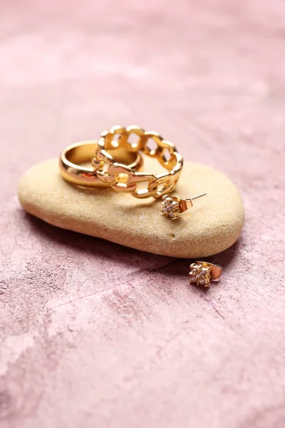 粉色背景的漂亮戒指和耳环的石头 — 图库照片